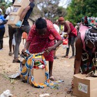 Home People collecting relief supplies in a community outdoor setting.